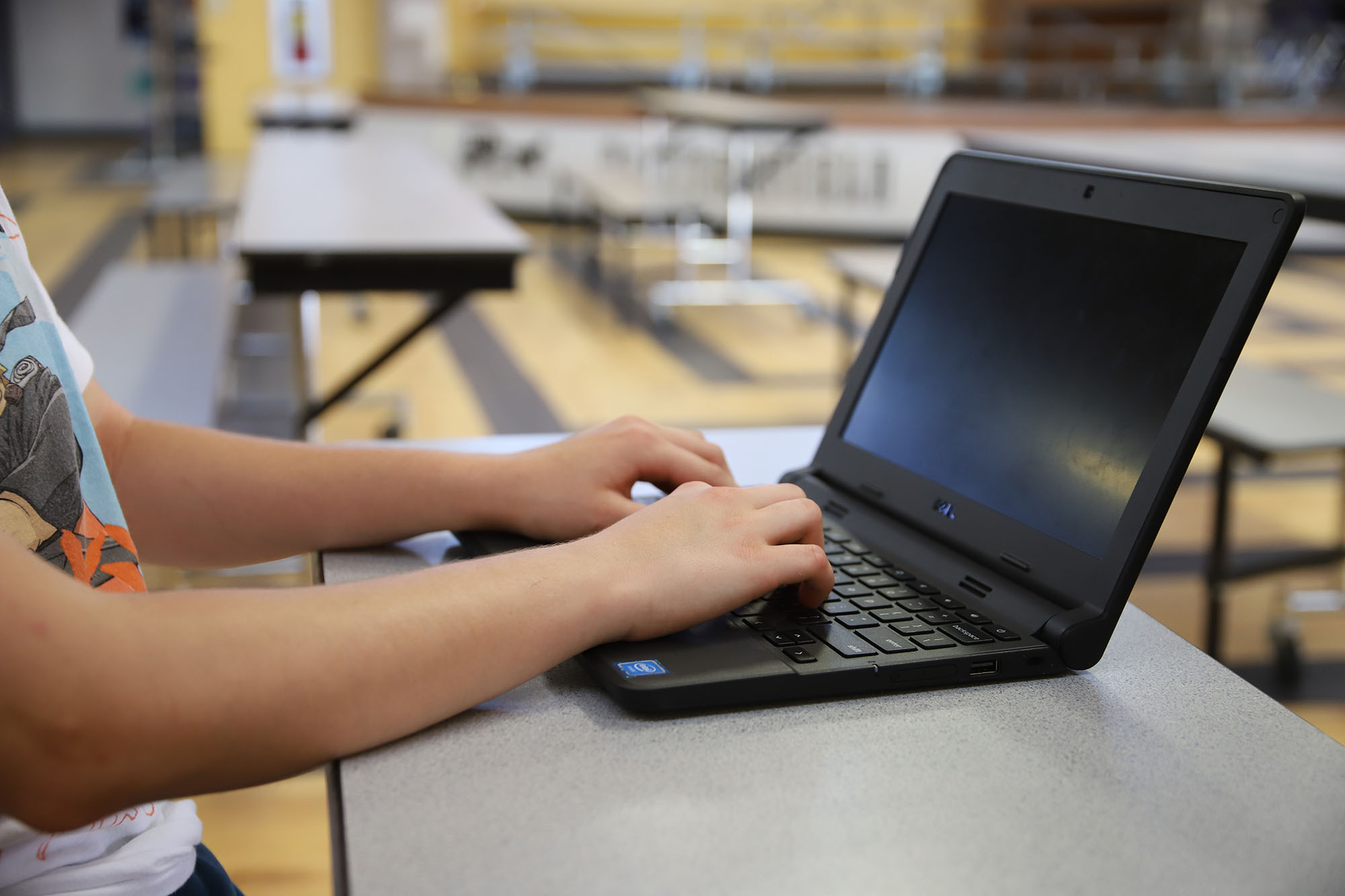 Student hands shown actively working on a Chromebook at school.